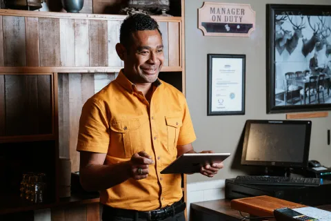 a man standing in front of a desk holding a tablet